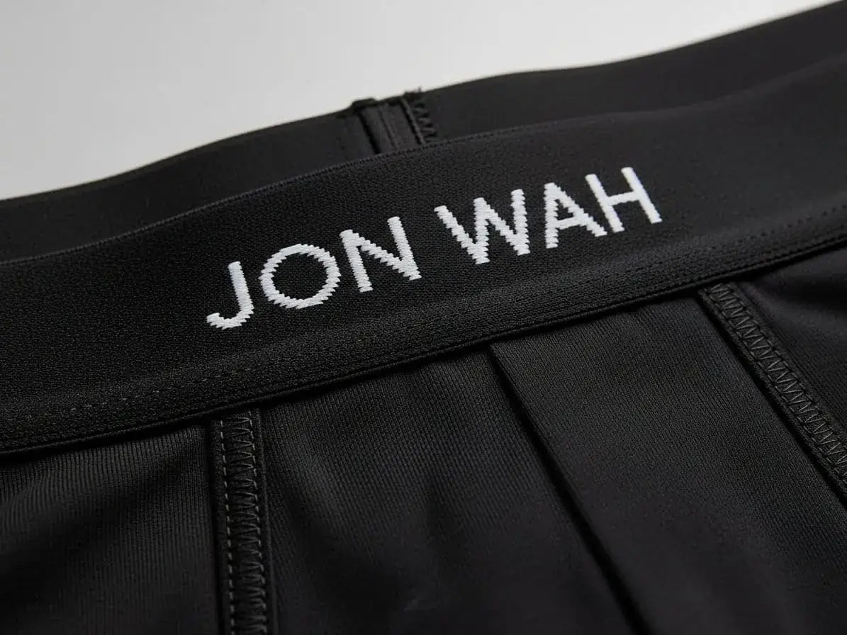 Black athletic shorts with 'JON WAH' branding on the waistband against a light gray background.